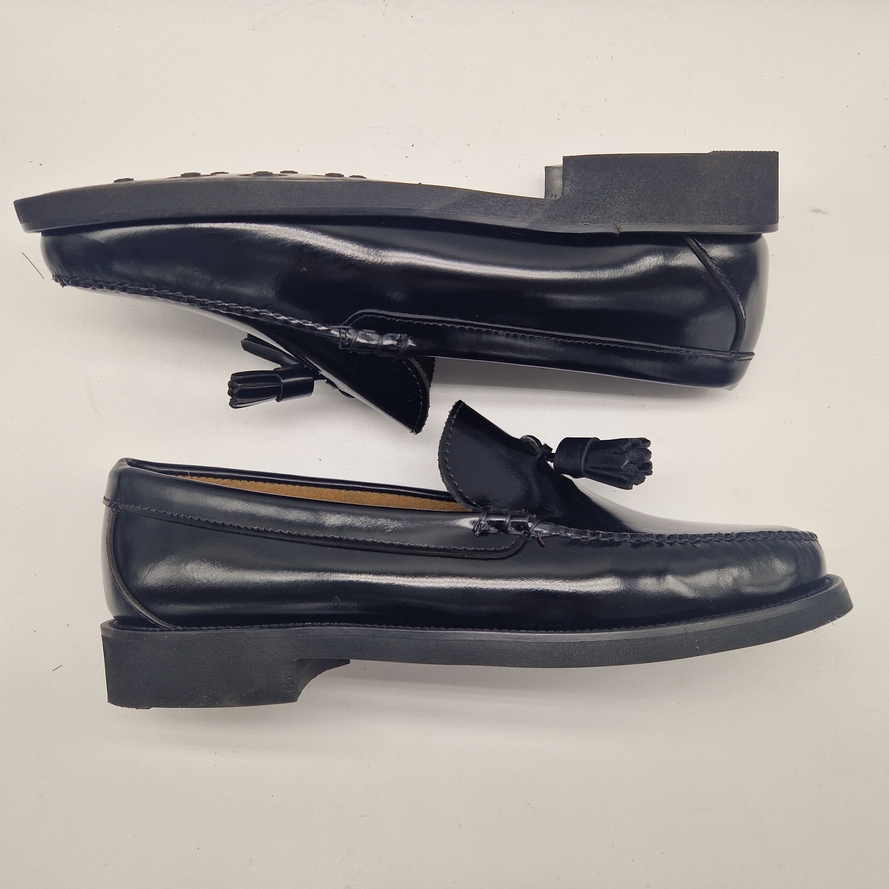 Vista lateral de zapatos castellanos de piel negra con borlas mostrando el perfil de la suela de goma robusta