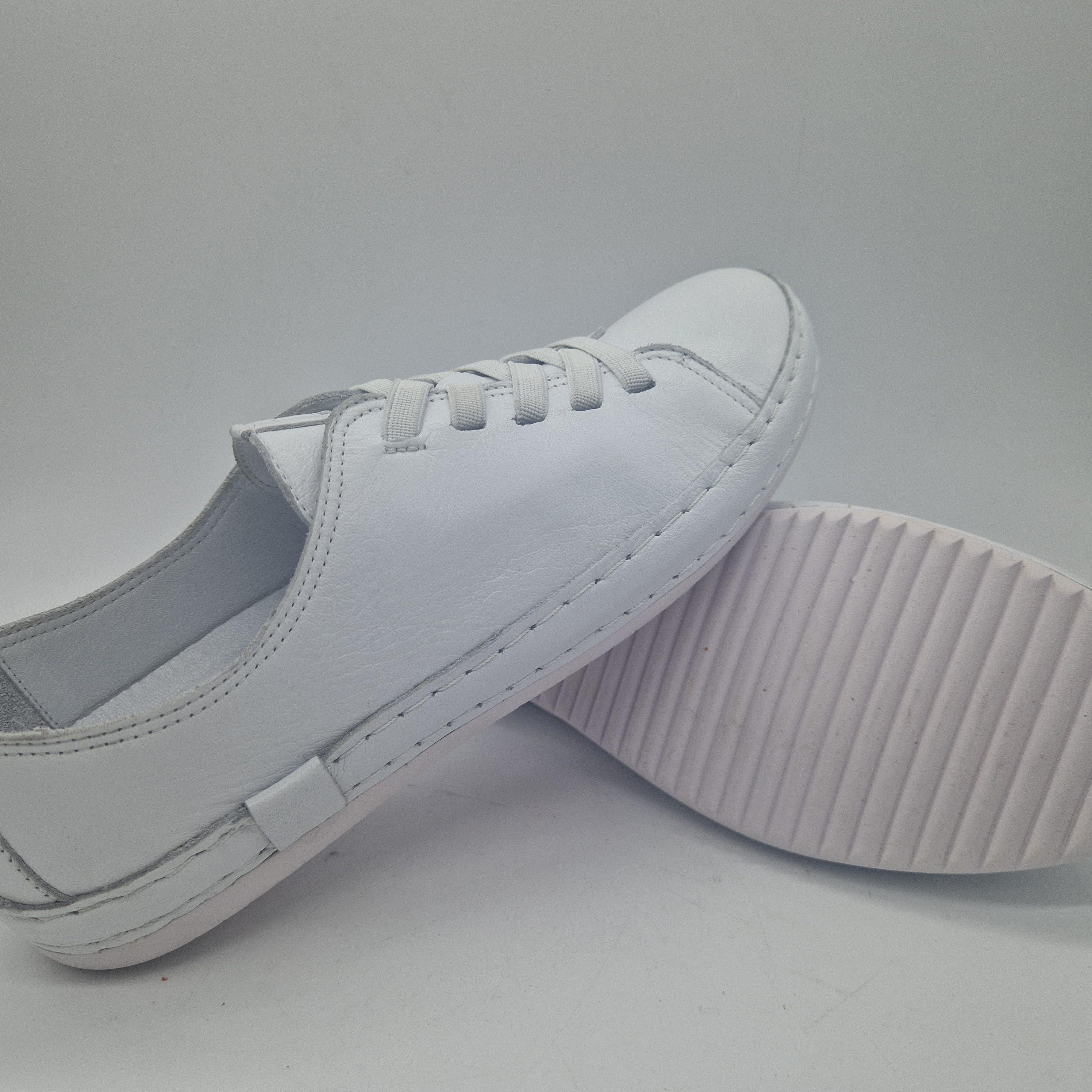 Zapatillas deportivas en piel blanca de Calzados Cremades, con detalles en azul y suela blanca.