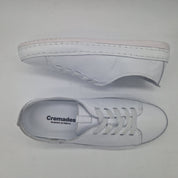 Zapatillas deportivas en piel blanca de Calzados Cremades, con diseño cómodo y moderno, vistas desde un ángulo lateral.