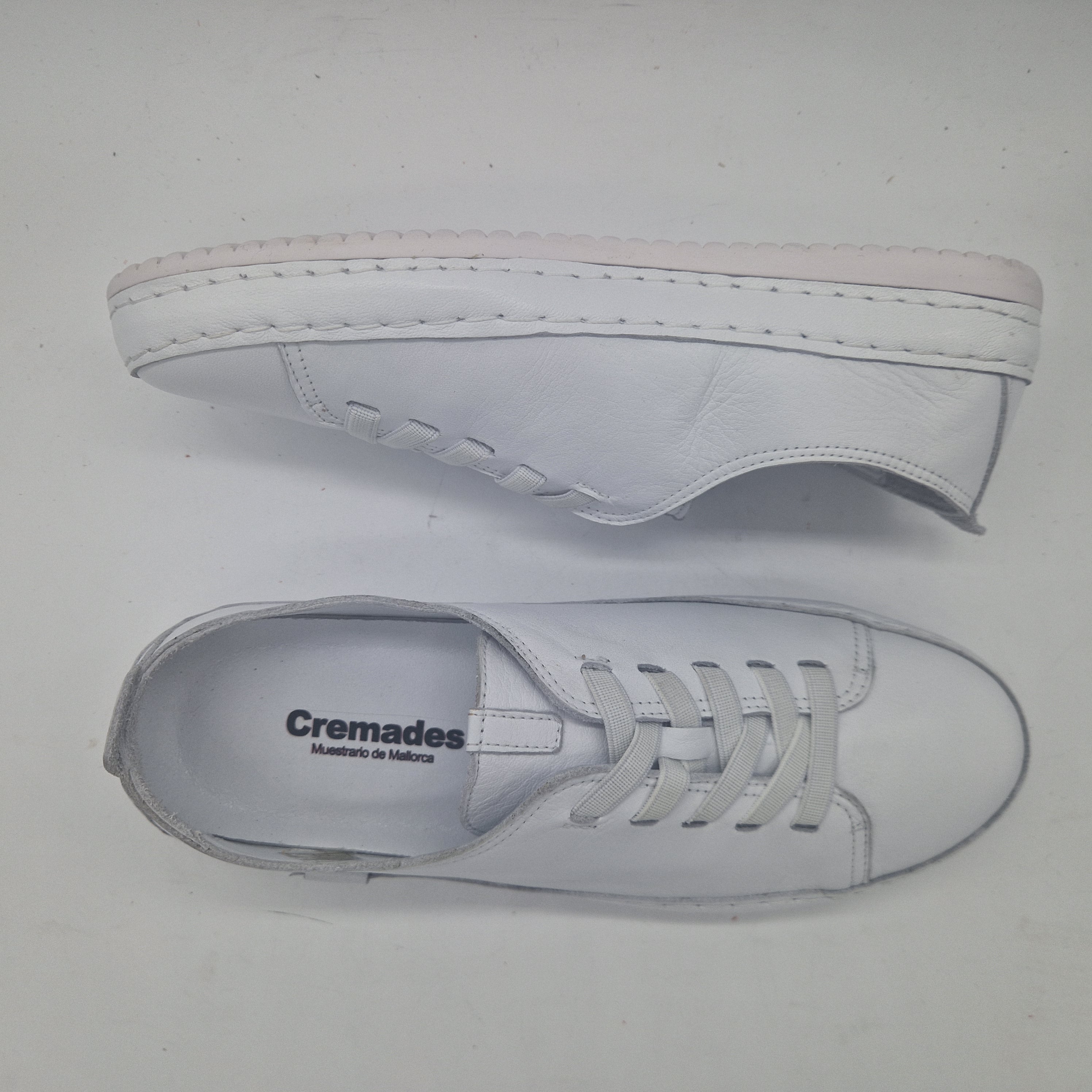 Zapatillas deportivas en piel blanca de Calzados Cremades, con diseño cómodo y moderno, vistas desde un ángulo lateral.