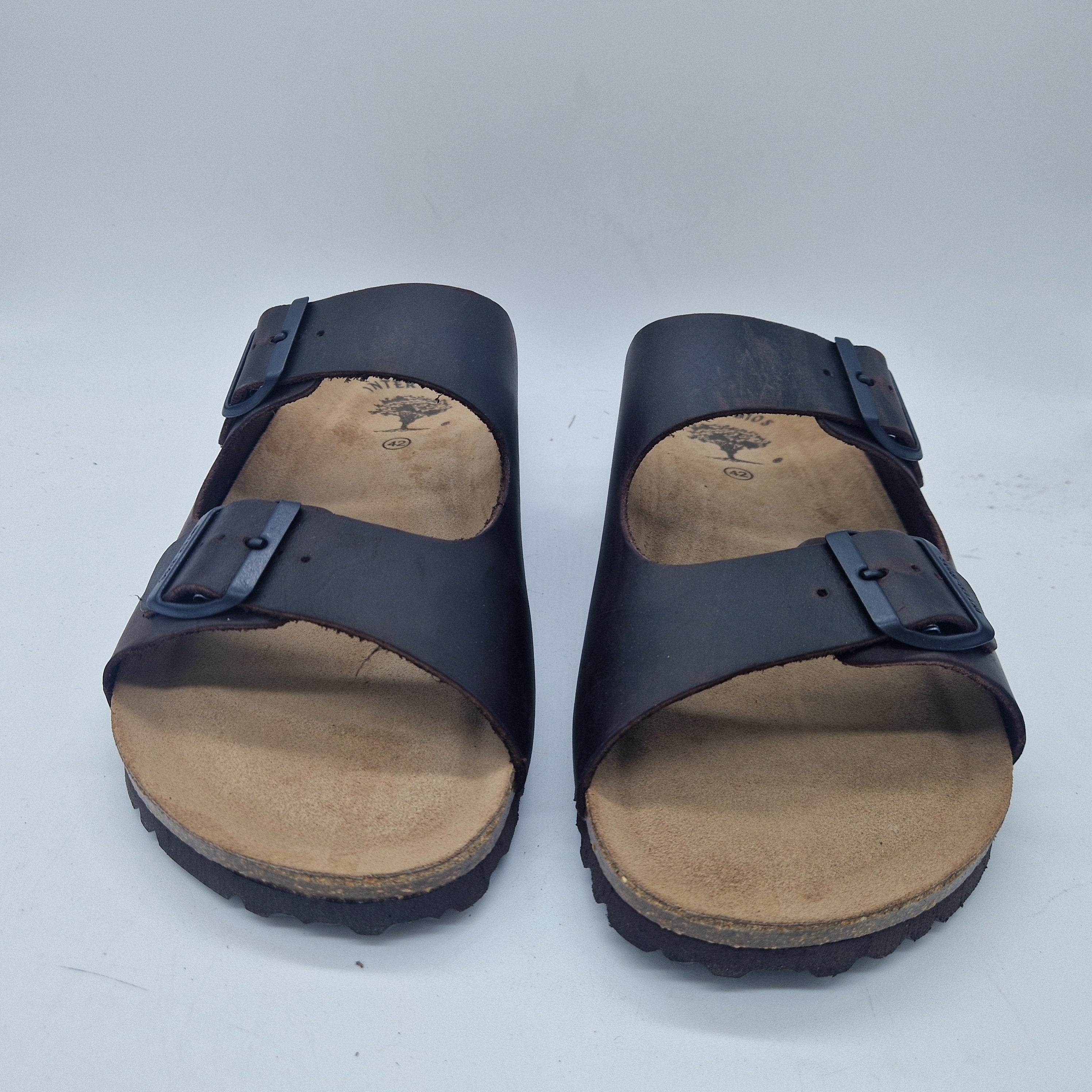 Sandalias Interbios de dos hebillas en marrón, con suela de piso fino y cómodo, ideales para verano y uso casual.