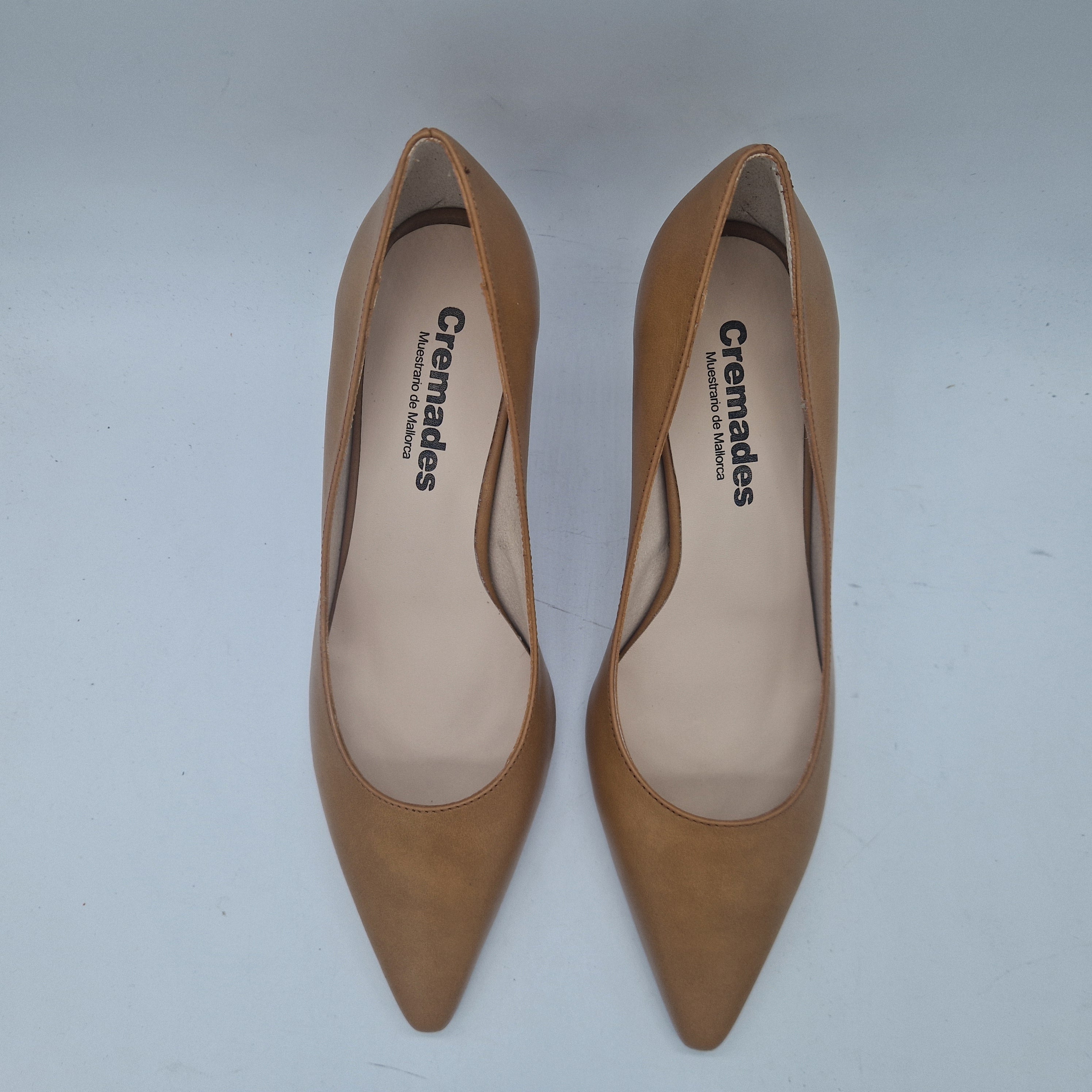 Sofá en piel color camel de la marca Patricia Miller, estilo salón moderno con cojines cómodos y patas de madera.