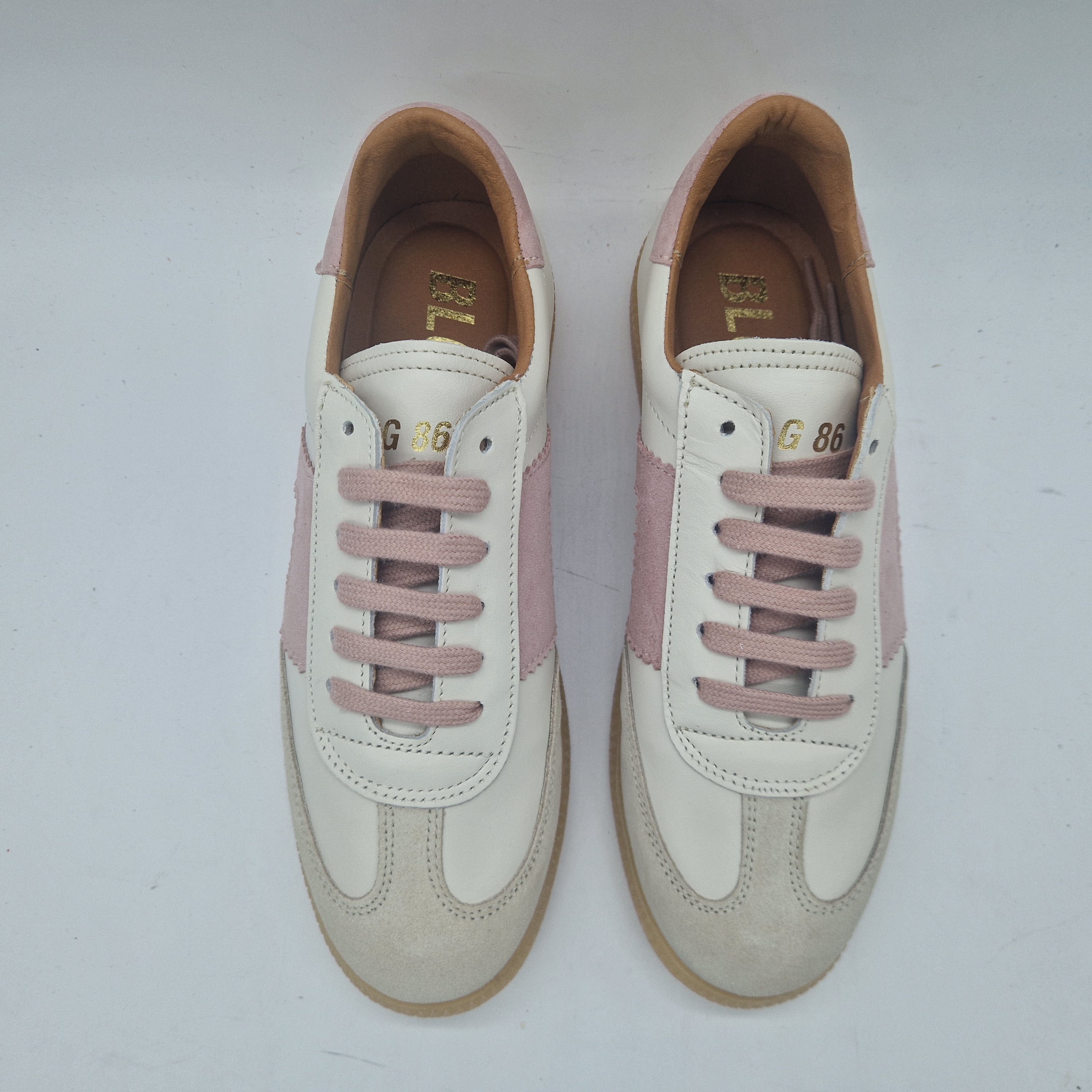 Deportivos en piel blanca con detalles en tonos rosas de Calzados Cremades, vista lateral y suela sólida.
