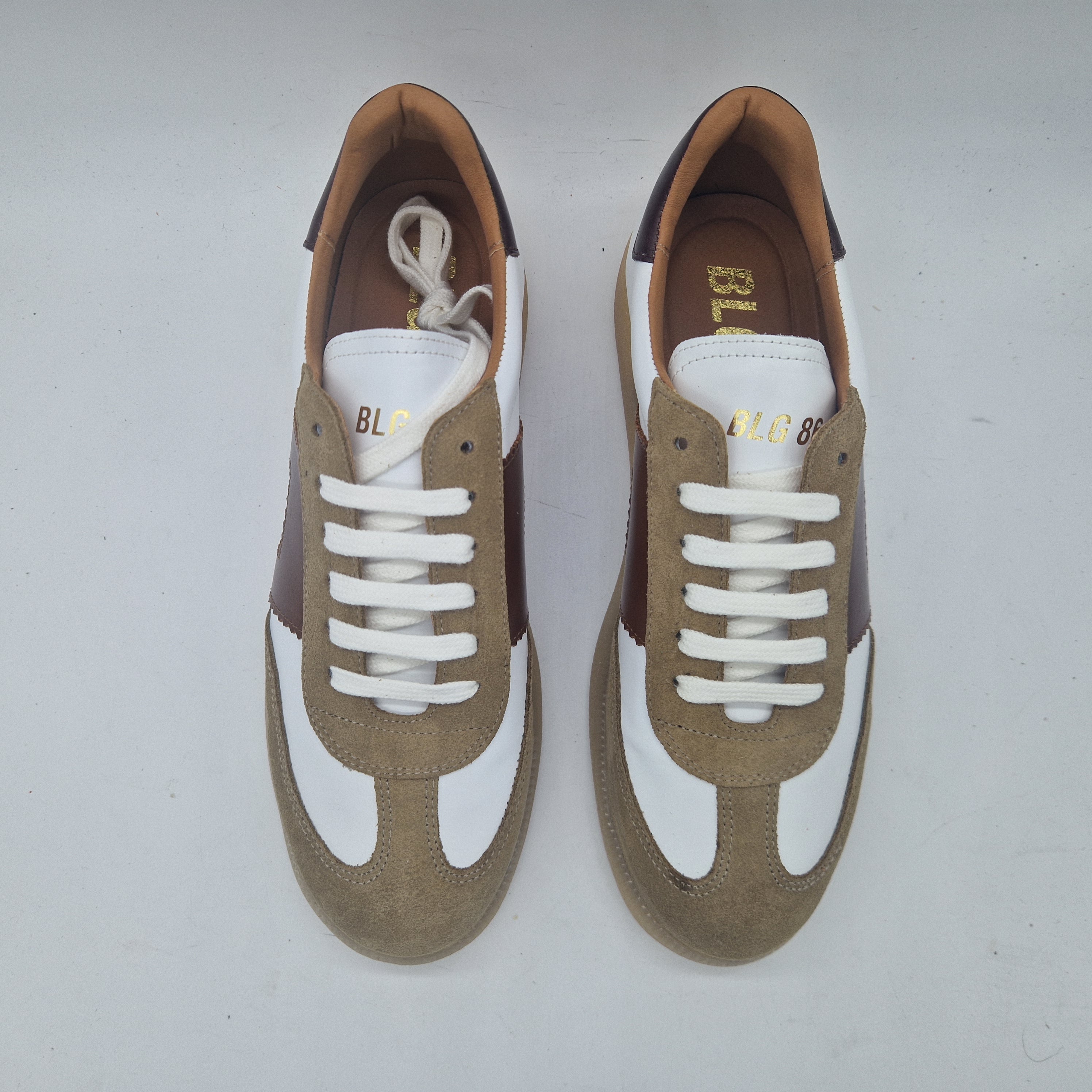 Deportivos en taupe y blanco de Calzados Cremades, vista lateral con detalles en la suela y diseño deportivo.